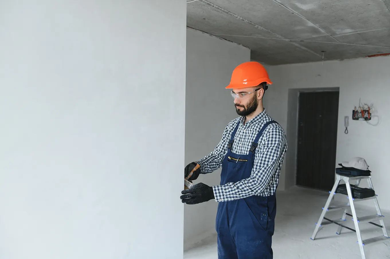 Construction worker measuring wall trim for precise installation in a new building project.