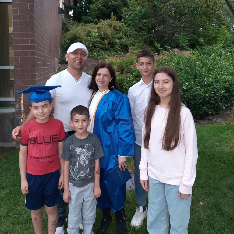 A happy family posing together at a graduation ceremony, celebrating an academic achievement.