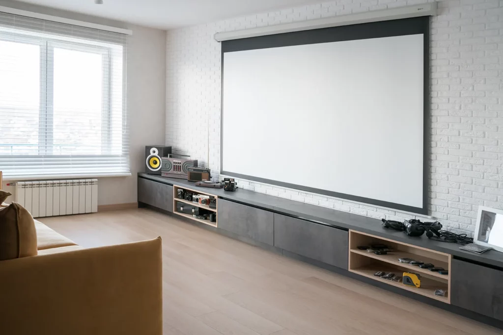 Modern home theater setup in a finished basement with a large projector screen and sleek audio equipment.