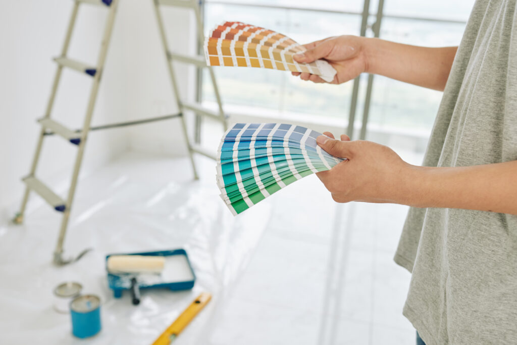 Person holding color swatches, selecting paint options for an interior painting project.