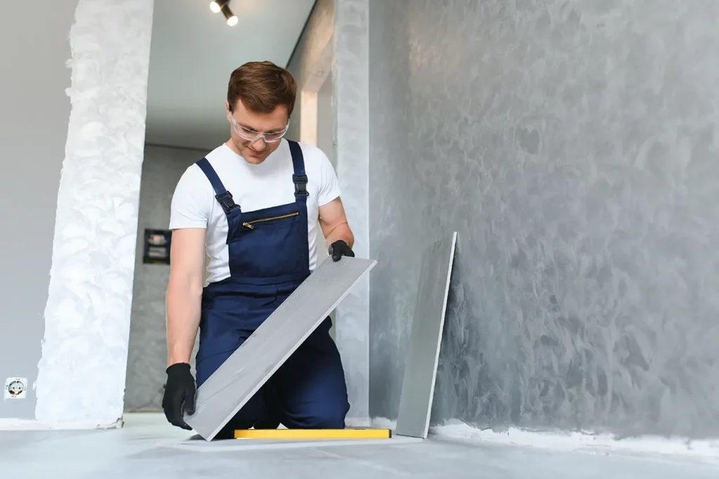 smiling worker installing gray floor tiles