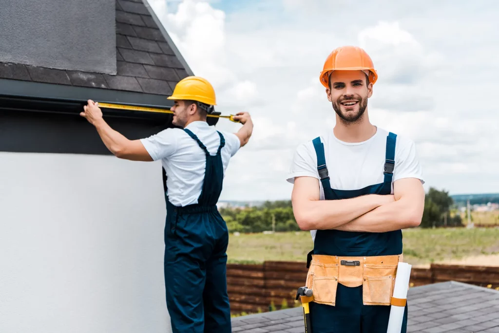 two workers are measure and installing gutter