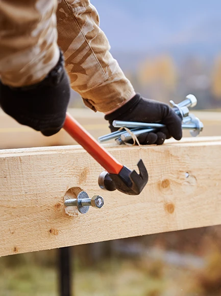 worker hammering a bolt into a wooden beam