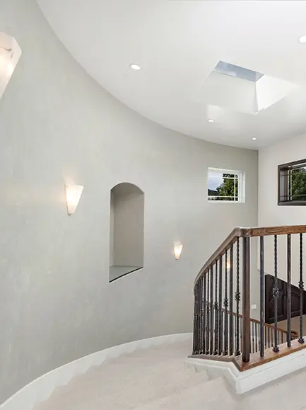 Elegant curved staircase with skylights and freshly painted light-colored walls.