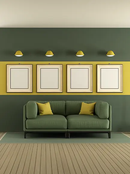 Modern living room with green and yellow accent walls, featuring a green sofa and framed wall art.