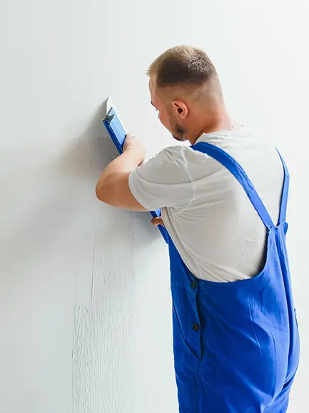 Professional painter applying a fresh coat of white paint to a residential wall.