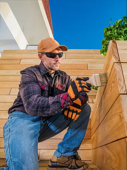 Man applying protective wood stain to outdoor deck