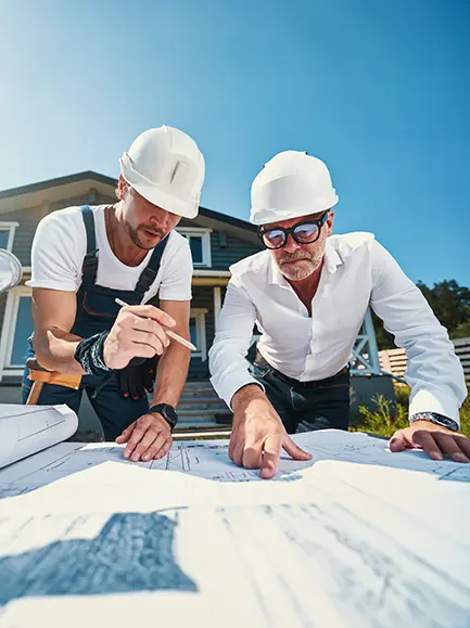 Two general contractors reviewing blueprints on a construction site in Spokane